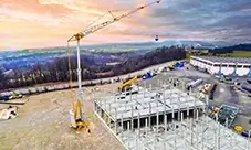 Potain HUP 32-27 on site, keeping material moving across the steel frame.